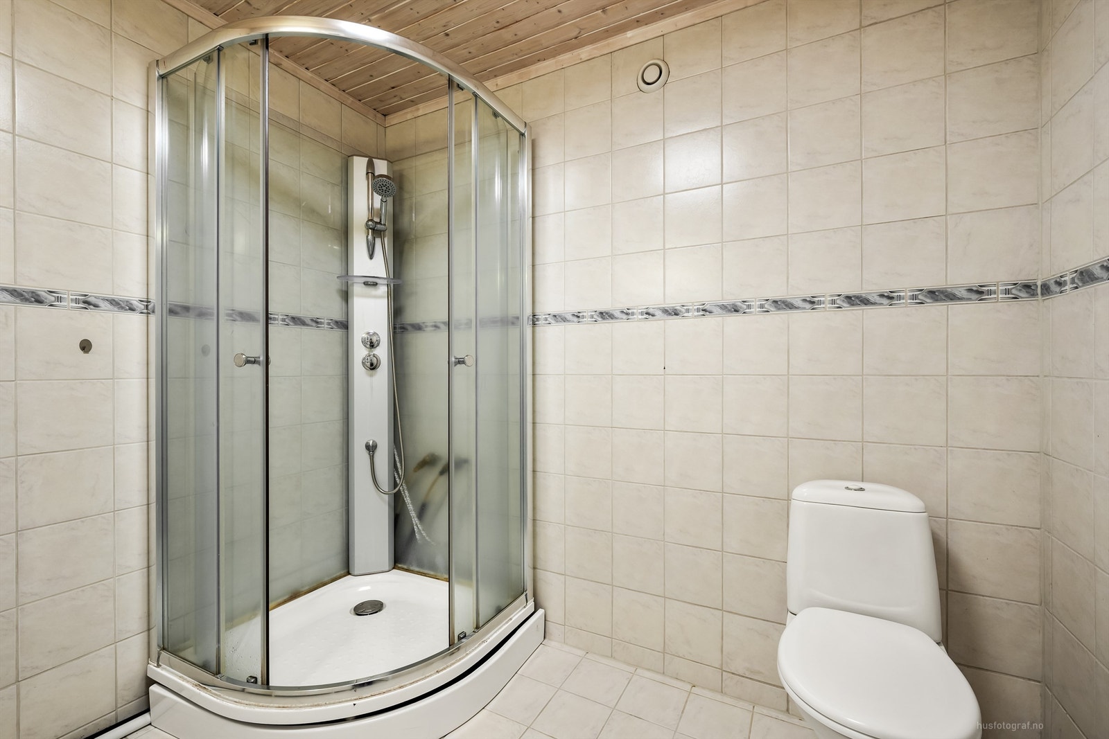 Badet er flislagt og har toalett og et romslig dusjkabinett. Galleribilde