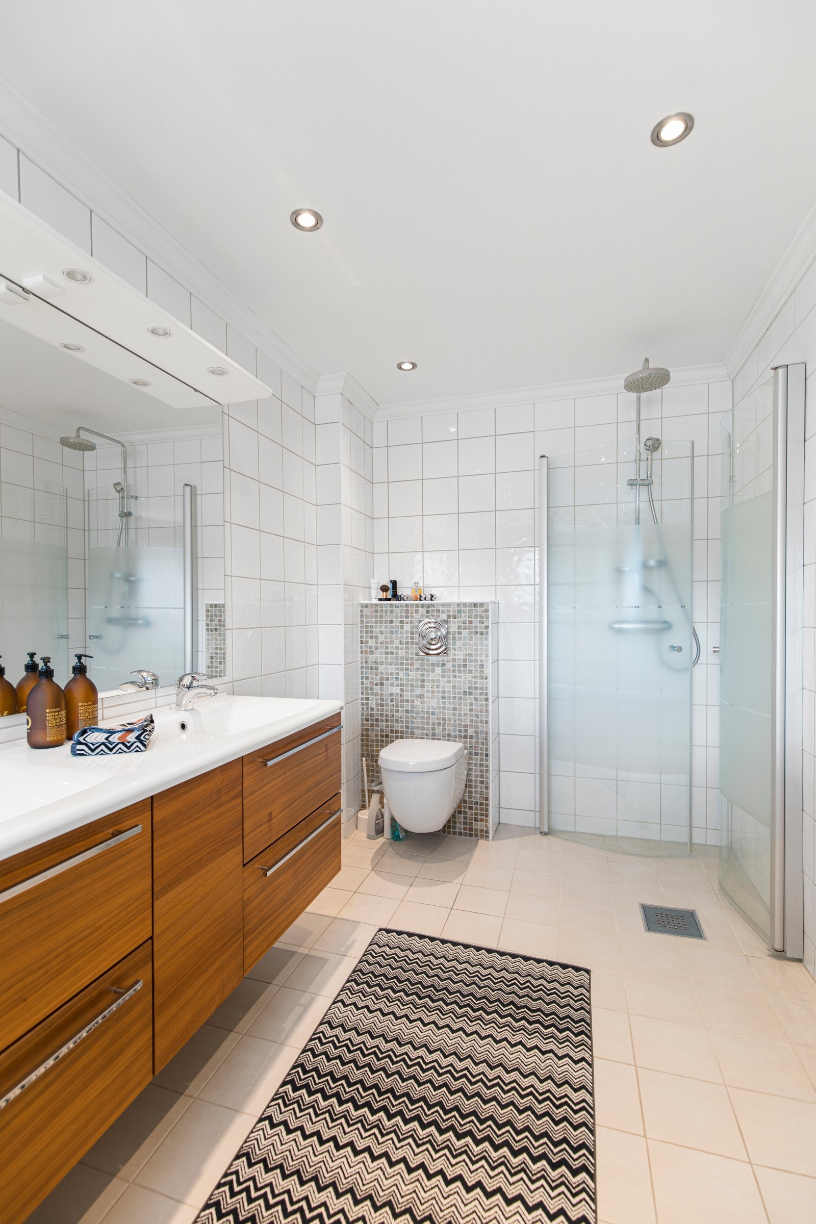 Rommet inneholder badekar, dusj med innfellbare vegger, vegghengt toalett og baderomsinnredning. Galleribilde