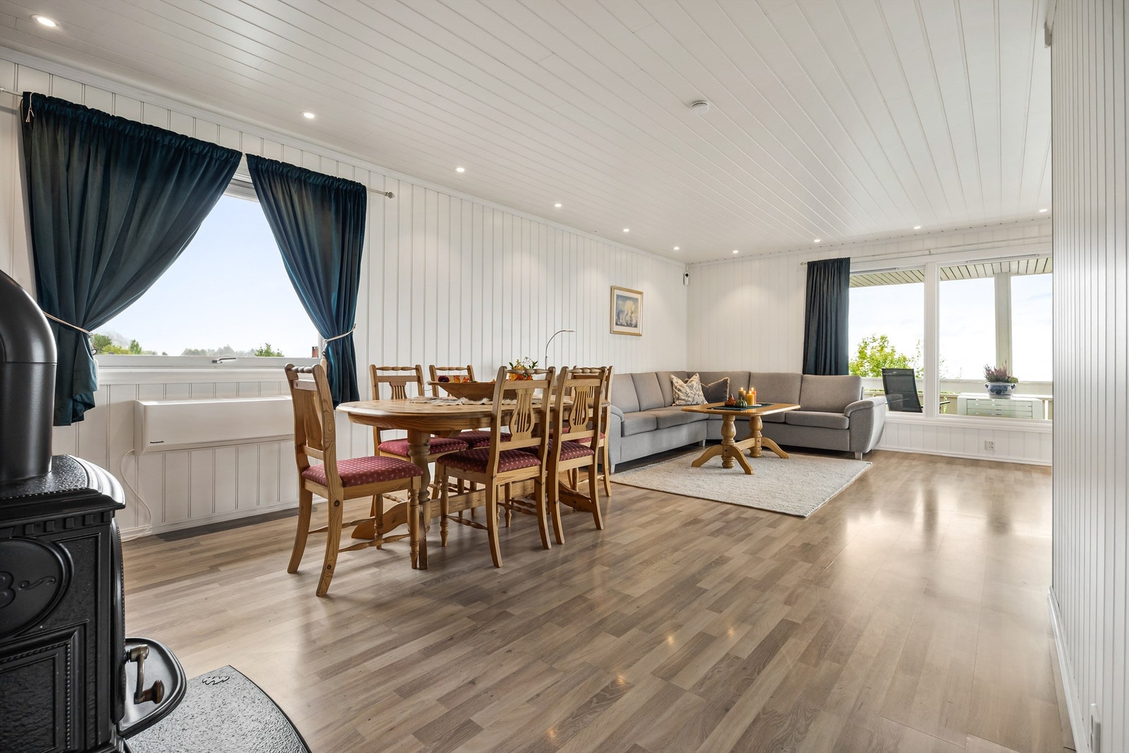 Lys vinkelstue med sofaområde og spiseplass. Galleribilde