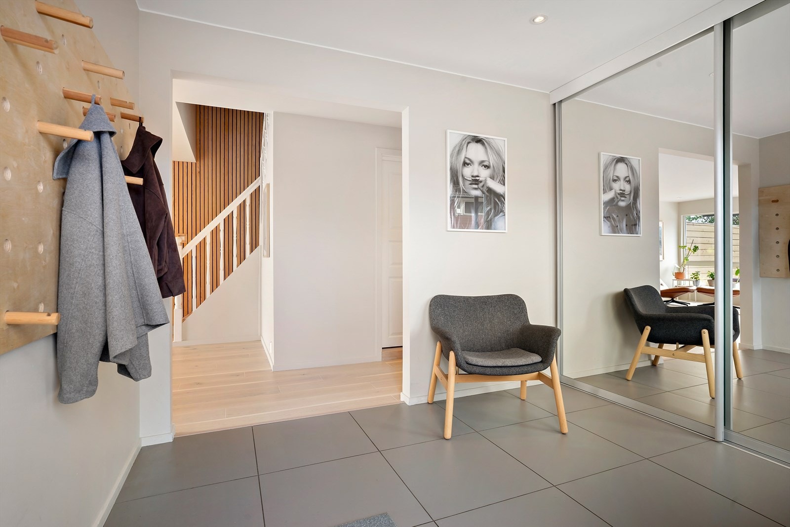Romslig entré med flislagt gulv og stor skyvedørsgarderobe med speilfronter. Galleribilde