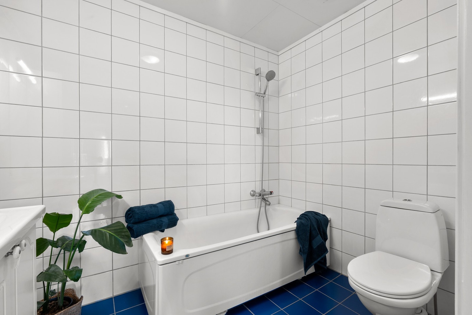 Flislagt baderom, med varme i gulv.Badet er utstyrt med gulvmontert klosett, og badekar med dusjutstyr og termostatstyrt blandebatteri. Galleribilde