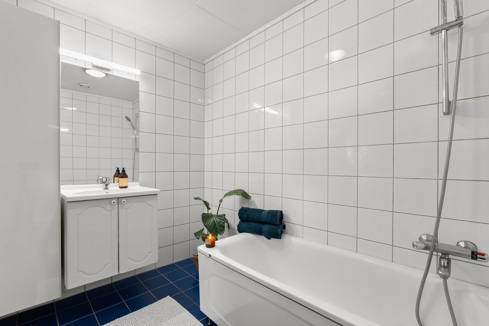 Servantskap med profilerte fronter og heldekkende servant. Speil med lysarmatur over servant. Badet er fra byggeåret. Galleribilde