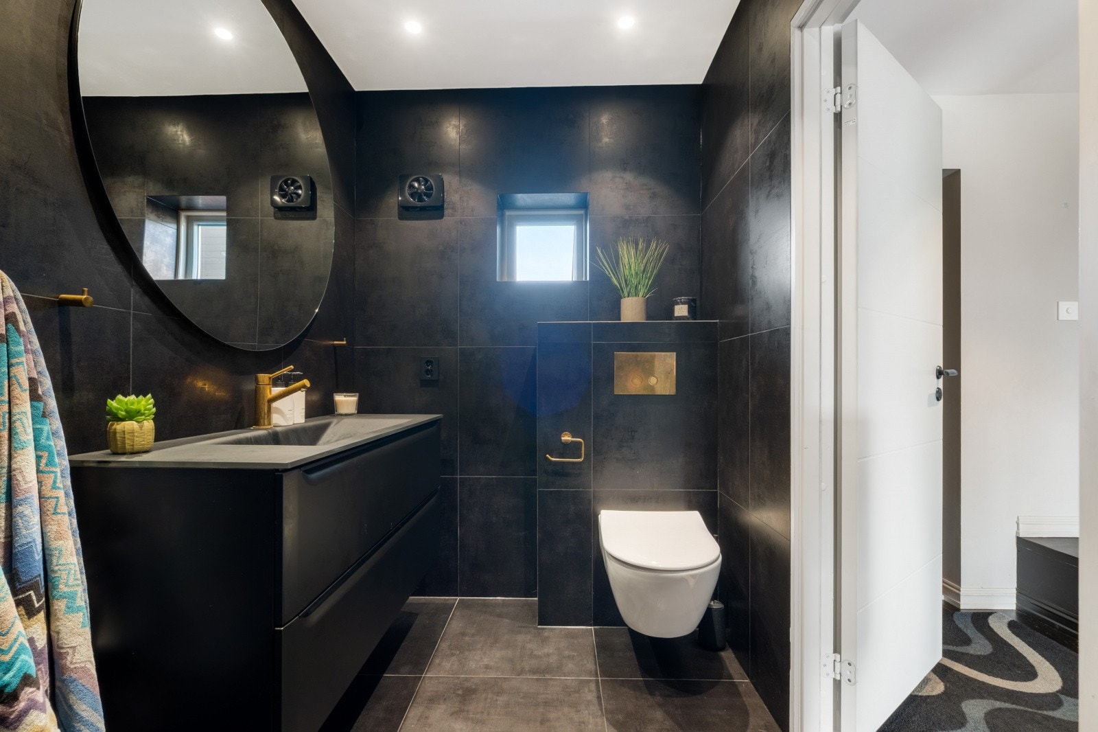 Badet er utstyrt med moderne innredning, veggmontert WC og dusjløsninger med glassvegger Galleribilde