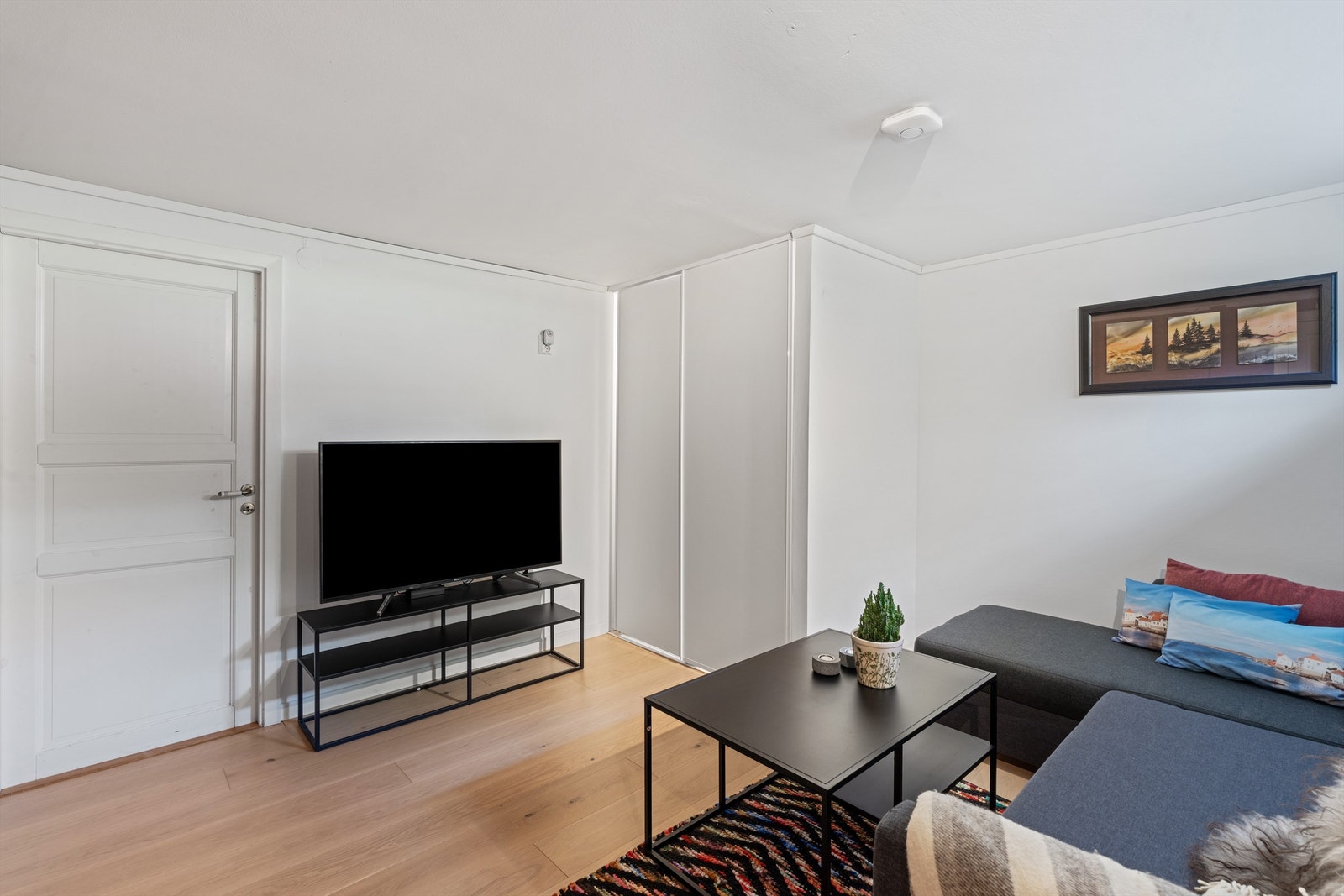 Kjellerrommet har parkett på gulv, malte vegger og plass til sofagruppe. Galleribilde