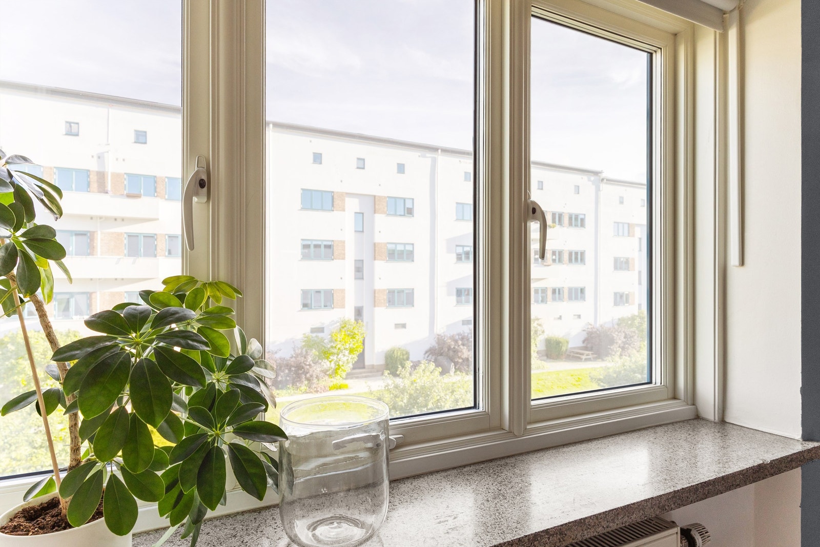 Dype vinduskarmer gir plass til grønne planter og ekte bygårdssjarm. Herfra ser du ned på Funkisgårdens skjermede og gartnerstelte bakgård, som blomstrer gjennom hele sesongen og er et populært samlingspunkt for naboene. Galleribilde