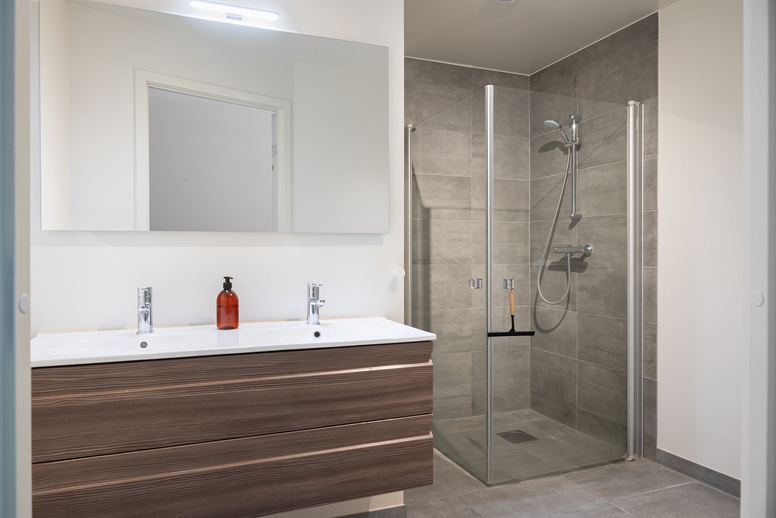 Badet har et tidløst uttrykk med fliser på gulv og i dusjsonen, samt vannbåren gulvvarme for ekstra komfort. Galleribilde