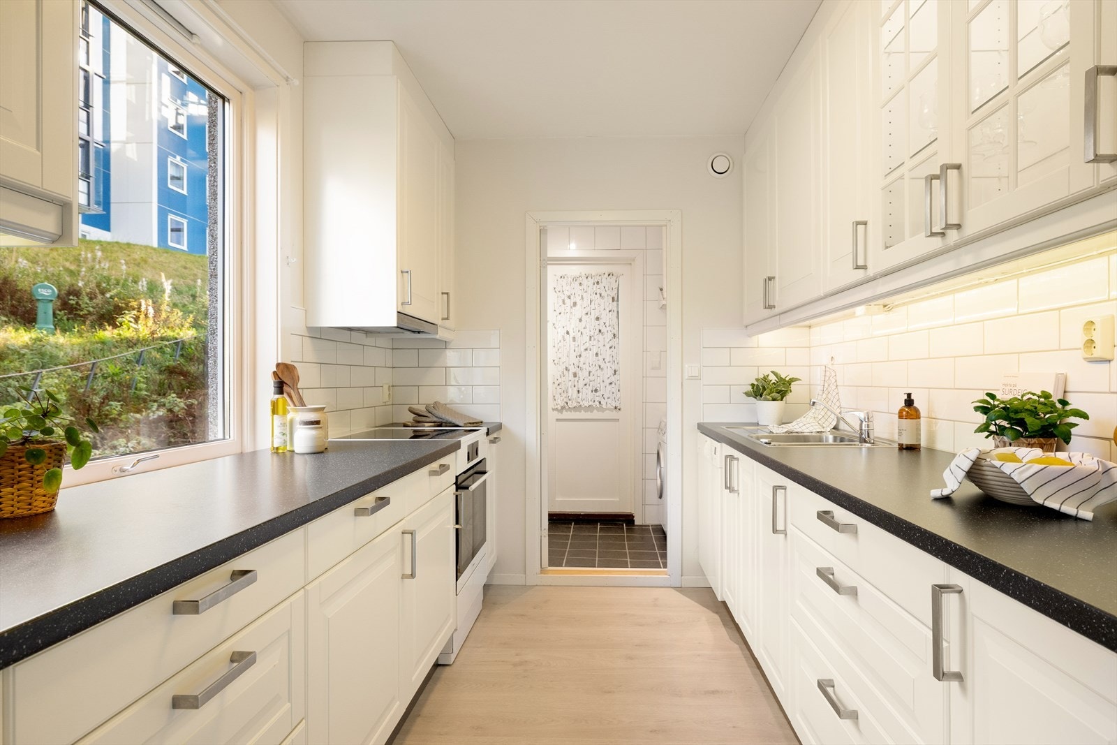 Separat og lyst kjøkken med innredning fra 2012. Kjøkkeninnredningen har profilerte fronter, laminert benkeplate og fliser mellom benkeplate og overskap. Galleribilde