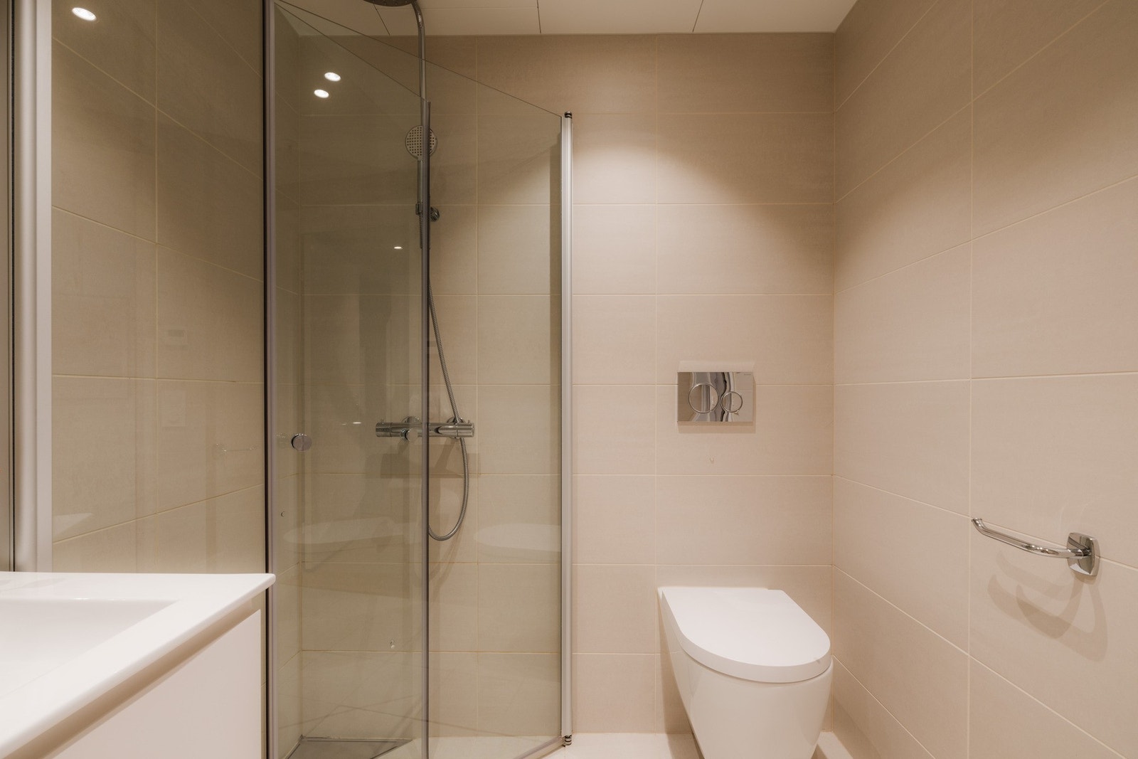 Badet fremstår delikat og moderne med flislagte overflater og dusjhjørne med glassvegger. Galleribilde