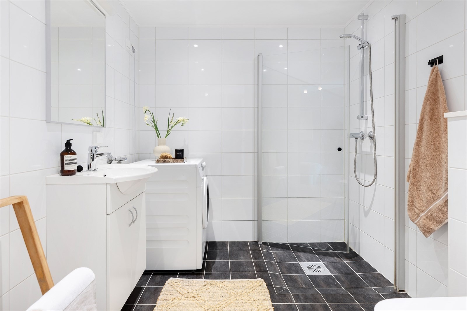 Badet inneholder servant, benkeskap, dusj med innfellbar dør i herdet glass, veggfestet toalett med innebygget sisterne og opplegg for vaskemaskin. Flislagt gulv med gulvvarme. Galleribilde