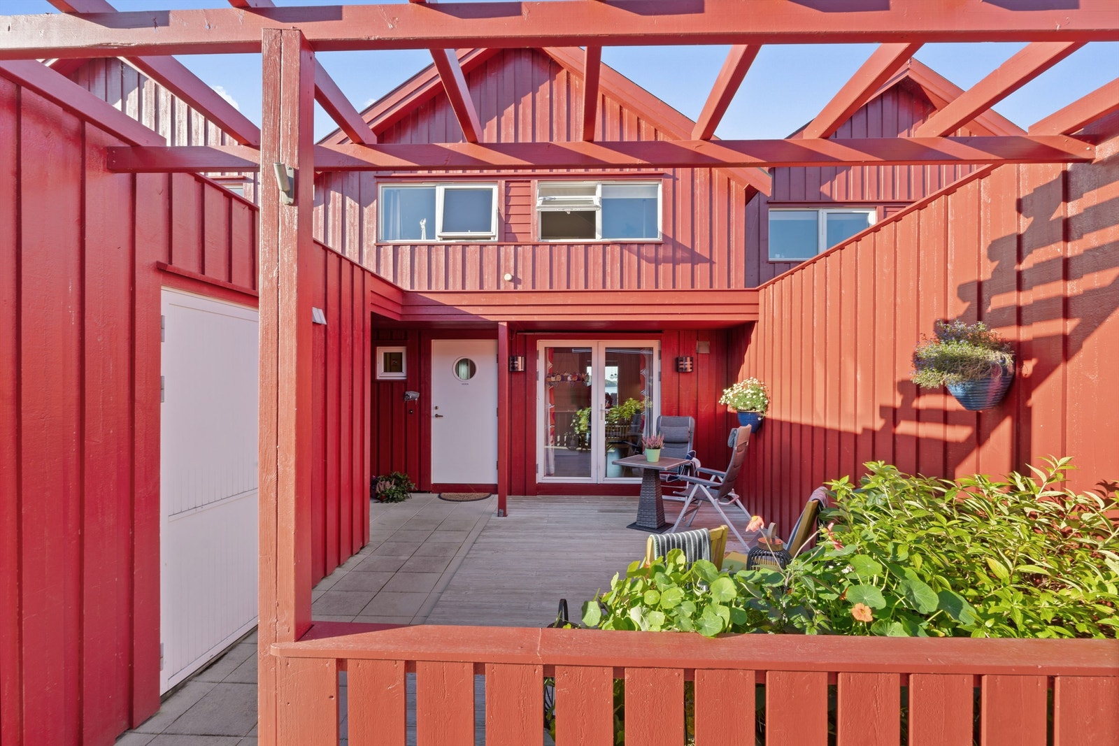 Skjermet terrasse belagt med terrassebord og betongheller ved inngangen. Galleribilde