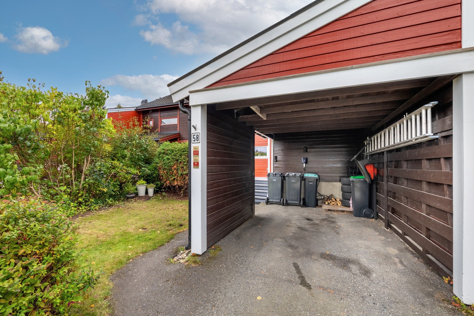 Det er parkering i carport med elbillader og på gårdsplass. Galleribilde