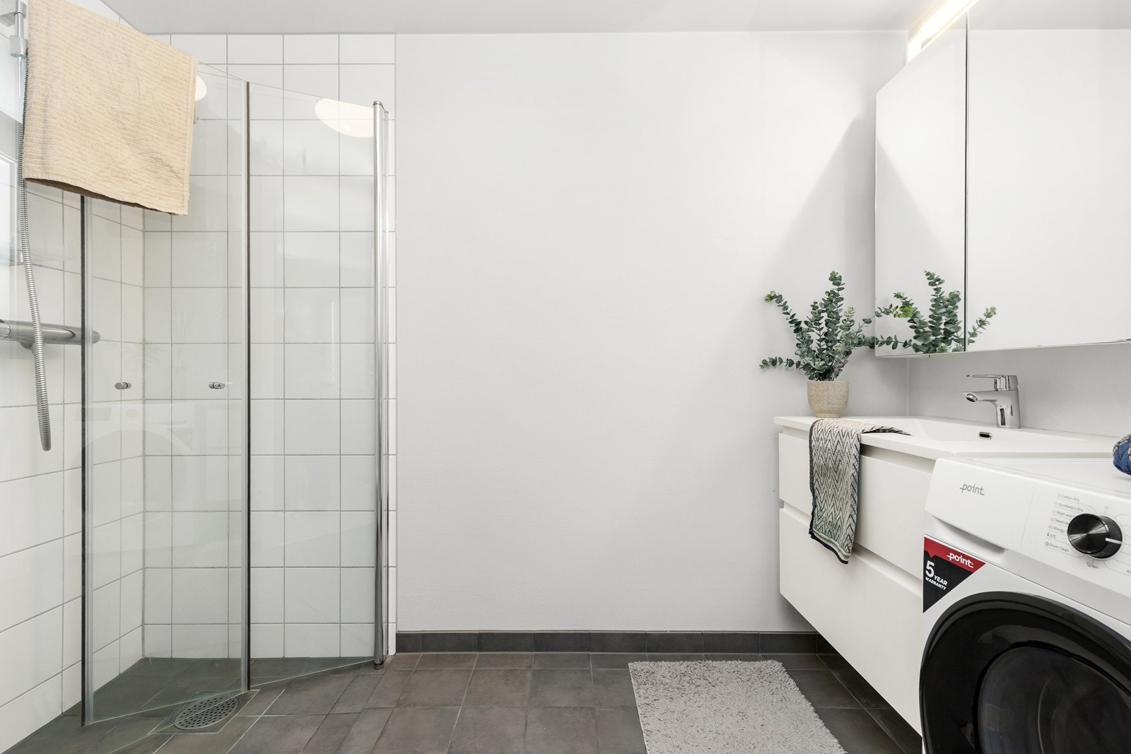 Badet er tidløst innredet med grå fliser på gulv, hvite fliser på vegg i dusjsone og ellers malte veggflater. I gulvet har man vannbåren varme for ekstra komfort. Galleribilde