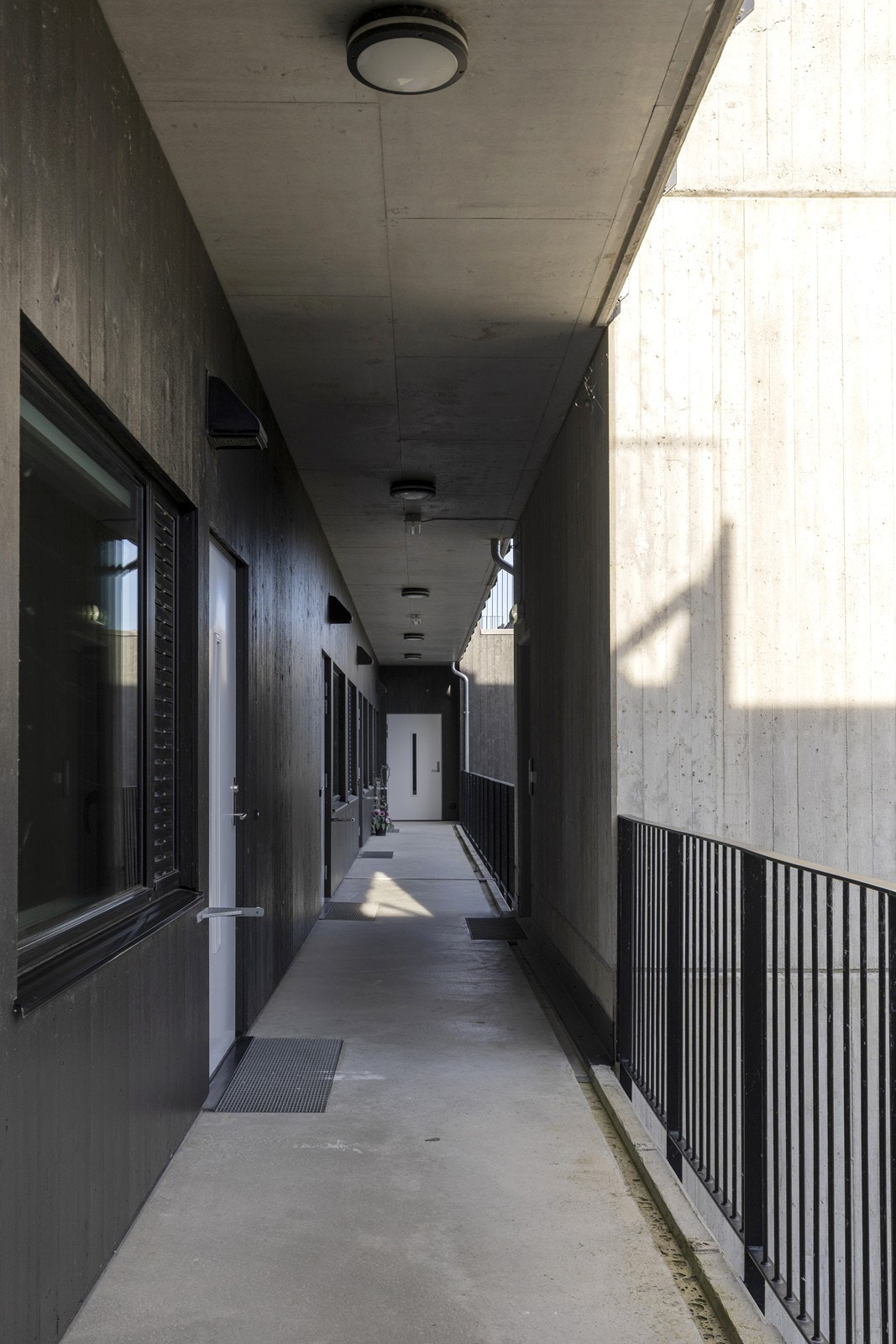 Adkomst til leiligheten via en overbygget svalgang med betongtrapper og heis i fellesområdene. Galleribilde