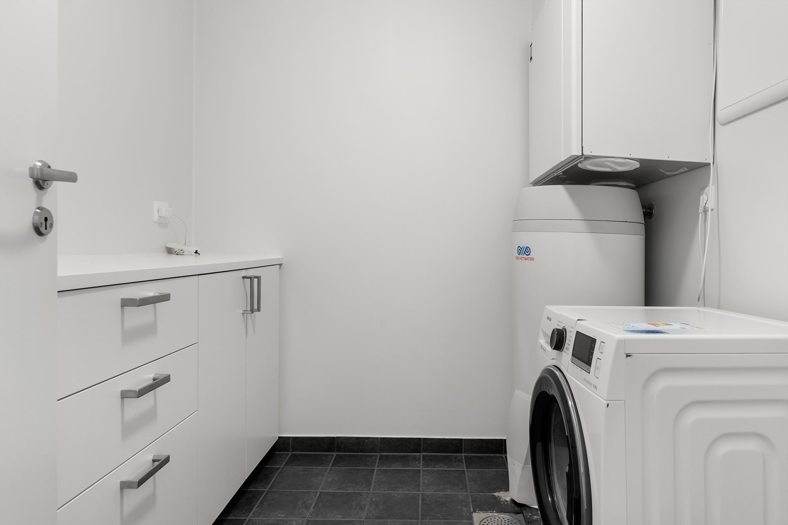 Vegg i vegg med badet er dett flislagt vaskerommet. Galleribilde