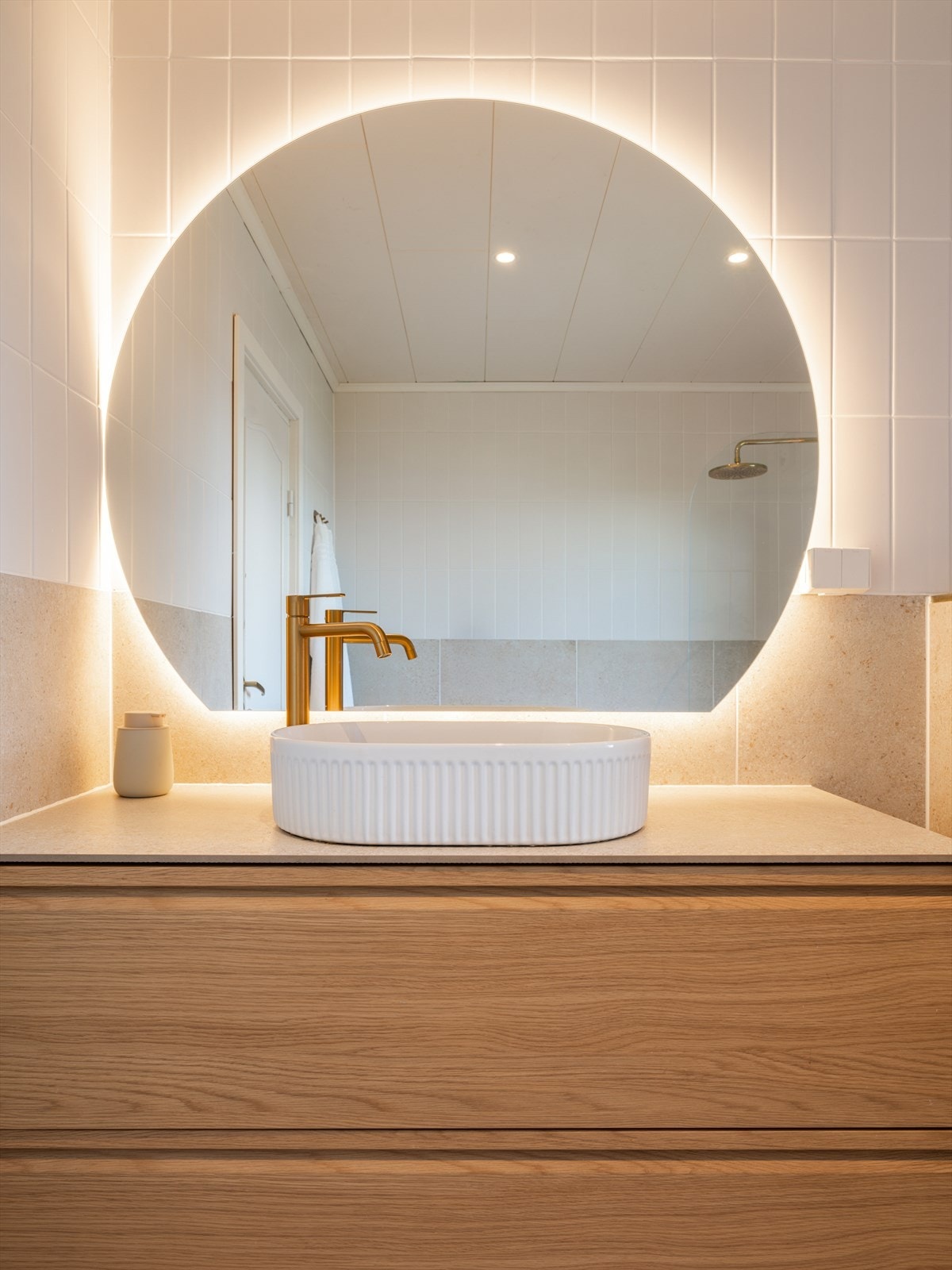 Badet er innredet med servant på skuffeinnredning, vegghengt toalett og speil med integrert belysning. Galleribilde