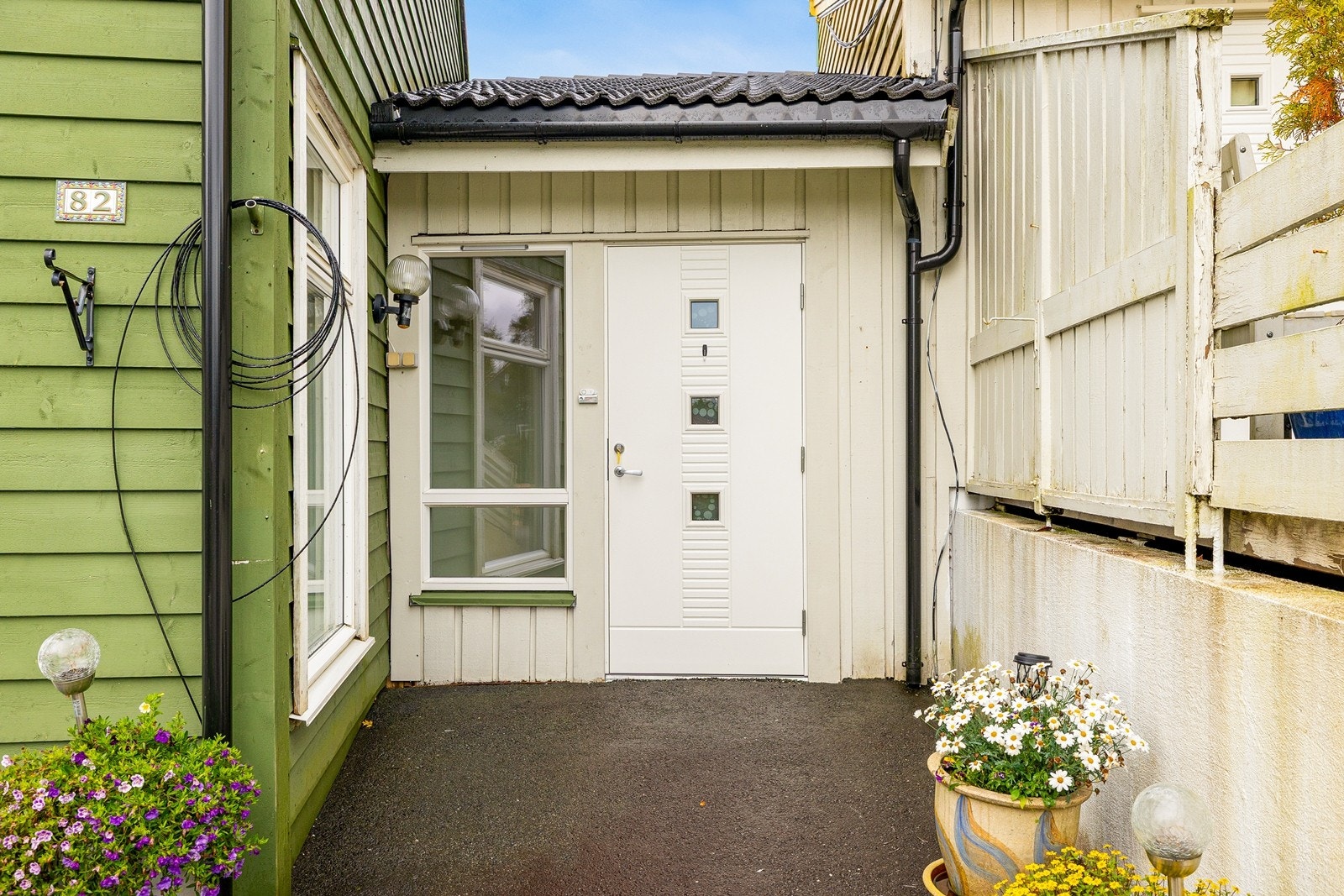 Skjermet inngangsparti med hvit ytterdør og glassfelt. Galleribilde
