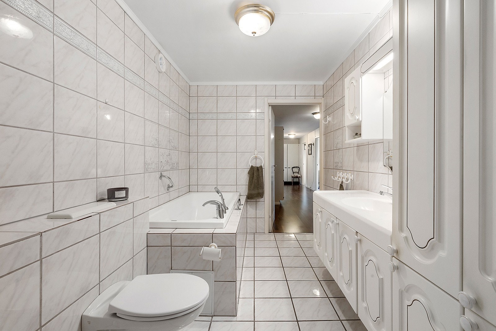 Innredningen består av servantinnredning med profilerte fronter og heldekkende topp, høyskap samt speil med belysning. Det er opplegg for vaskemaskin. Galleribilde