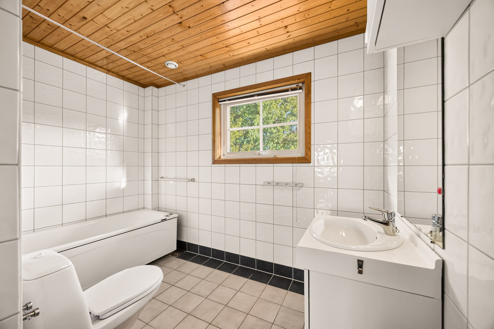 Baderom med flislagte overflater, badekar og rør-i-rør-system. Badet krever oppussing. Galleribilde