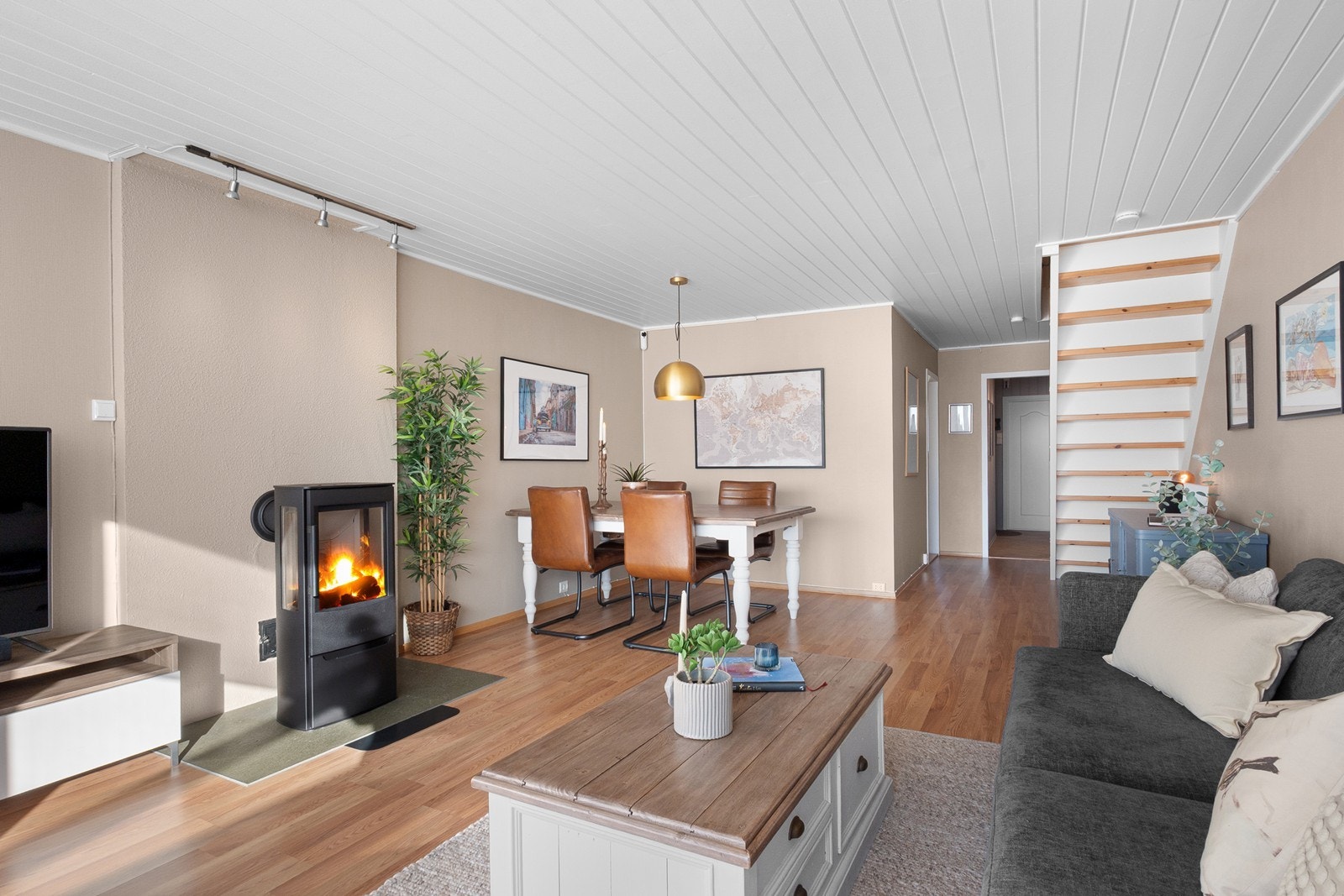 Stuen har god bredde og gir plass til både sofagruppe og et romslig spisebord, mens vedovnen tilfører varme og atmosfære. Galleribilde