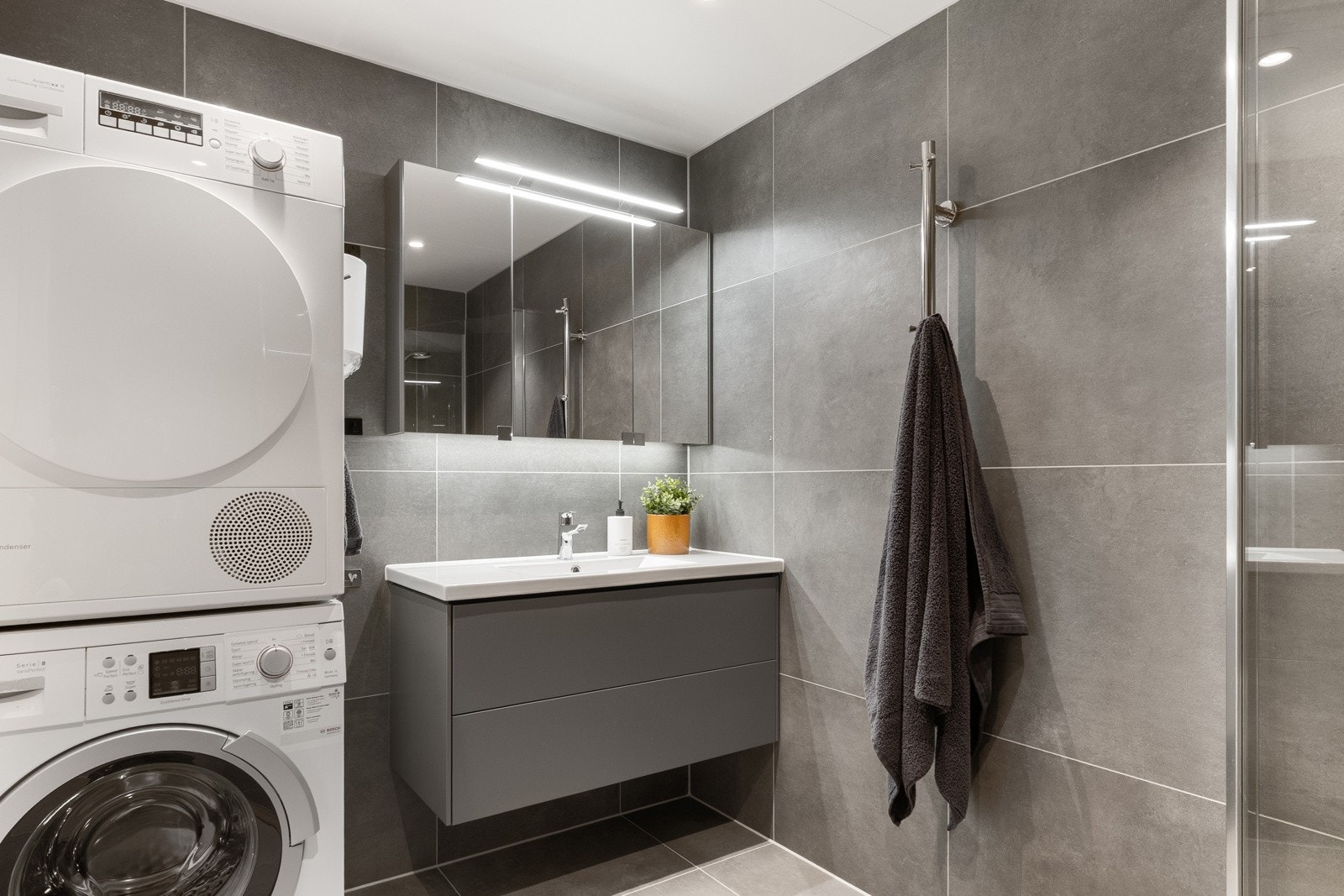 Badet har dusjløsning, servantinnredning og opplegg for vaskemaskin. Galleribilde