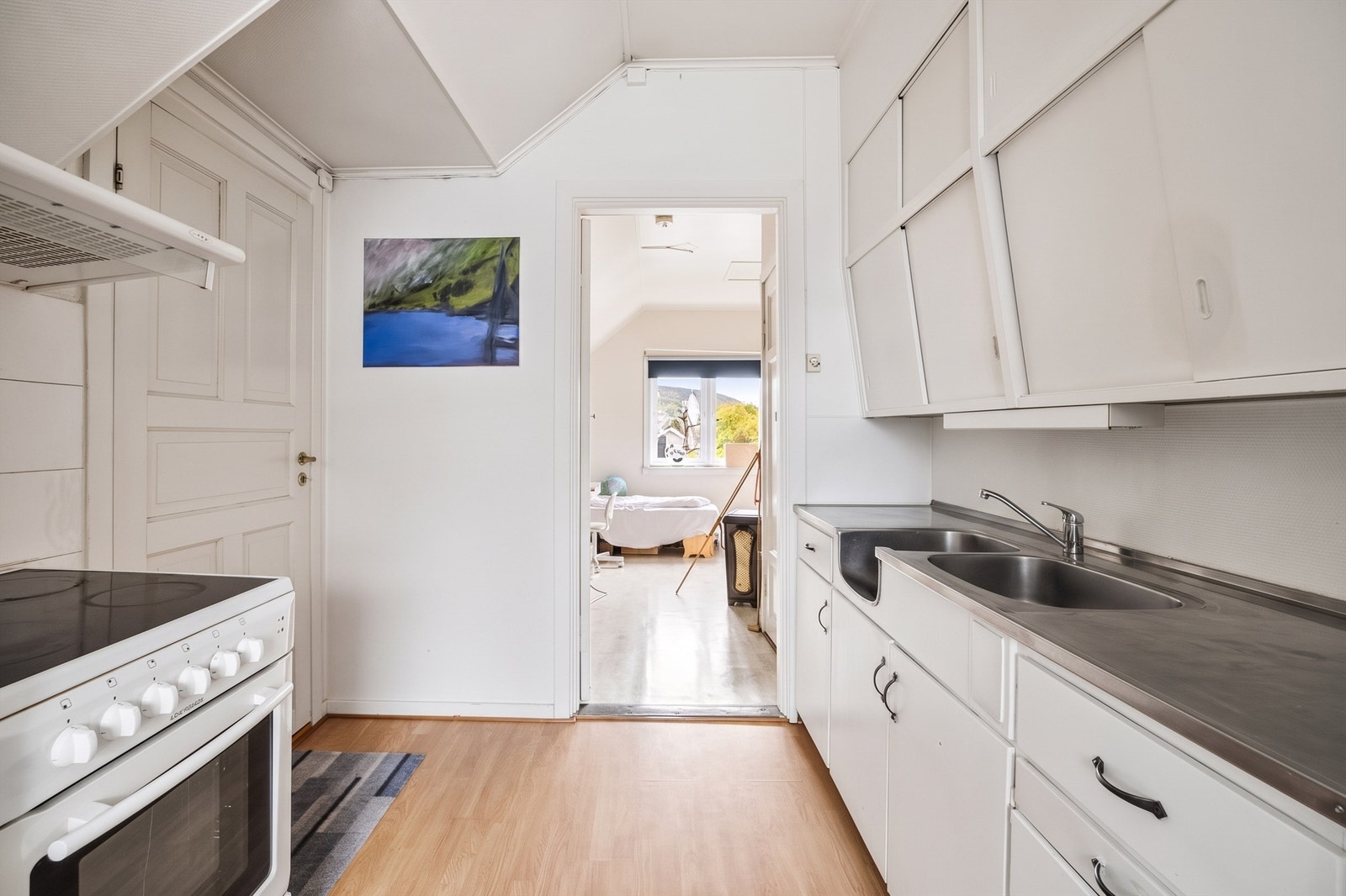 Kjøkkeninnredning med glatte fronter og benkeplate av rustfritt stål med nedfelt oppvaskkum. Galleribilde