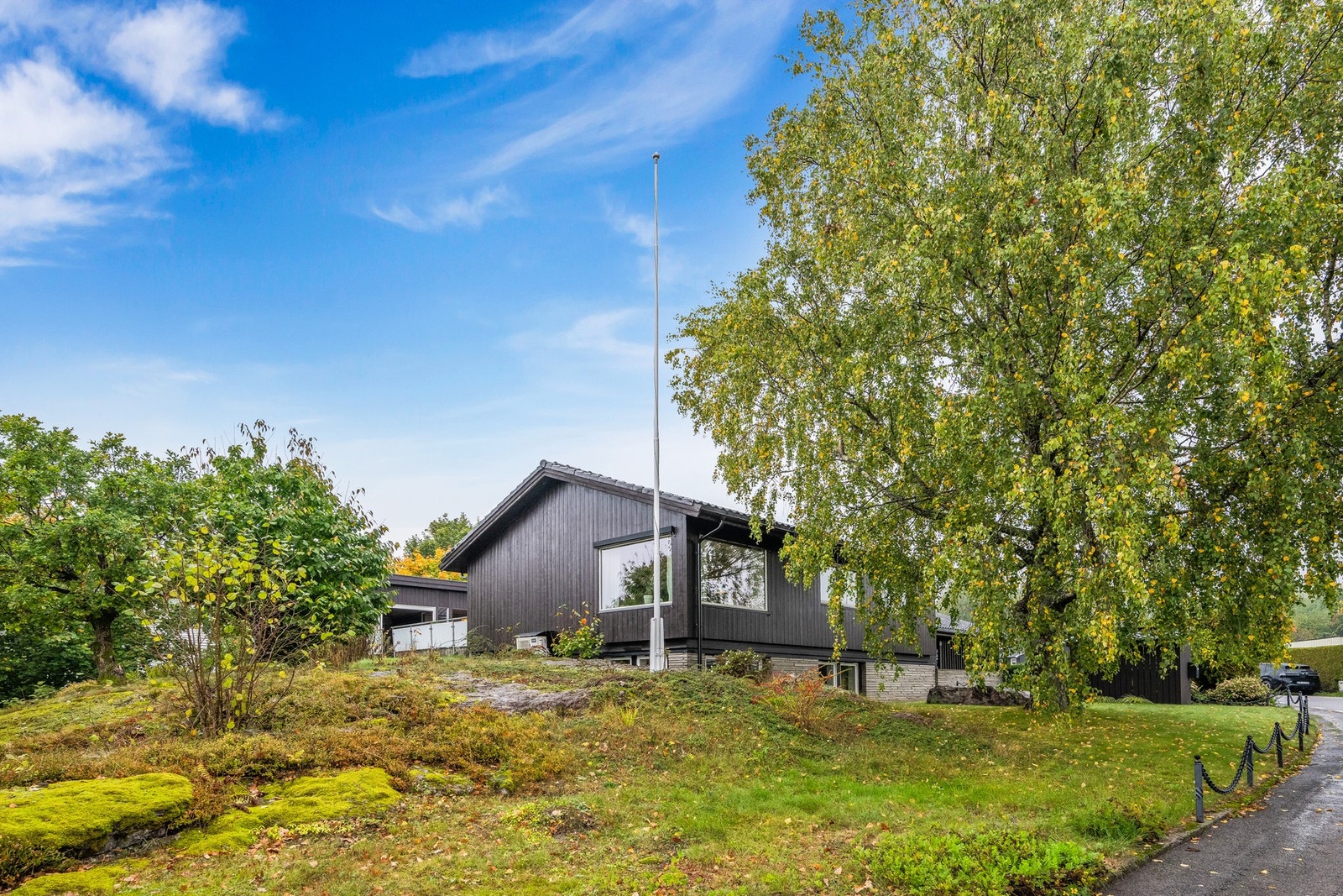Lettstelt, solrik og variert tomt med plen, beplantning, naturtomt og store steinsatte arealer Galleribilde