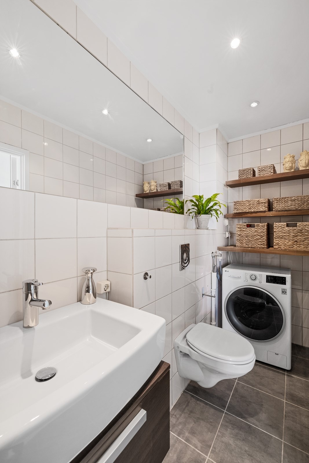 Badet har veggmontert toalett og opplegg for vaskemaskin Galleribilde