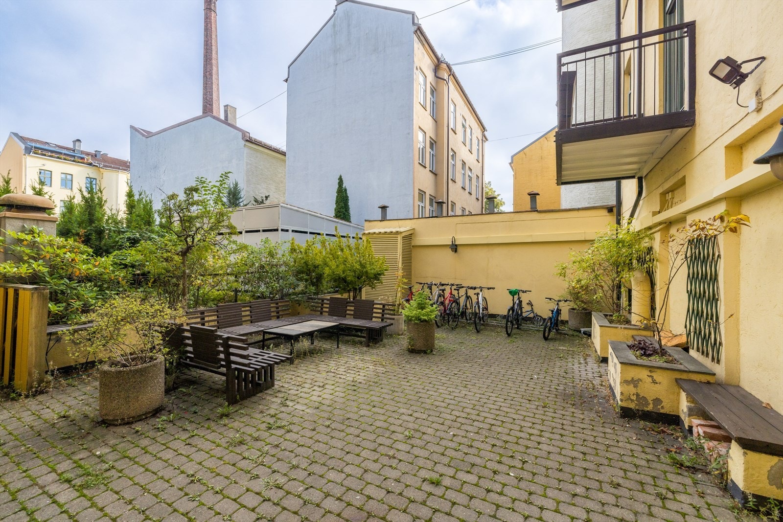 Sameiet byr på en skjermet og hyggelig bakgård med sitteplasser, grøntarealer og sykkelparkering Galleribilde