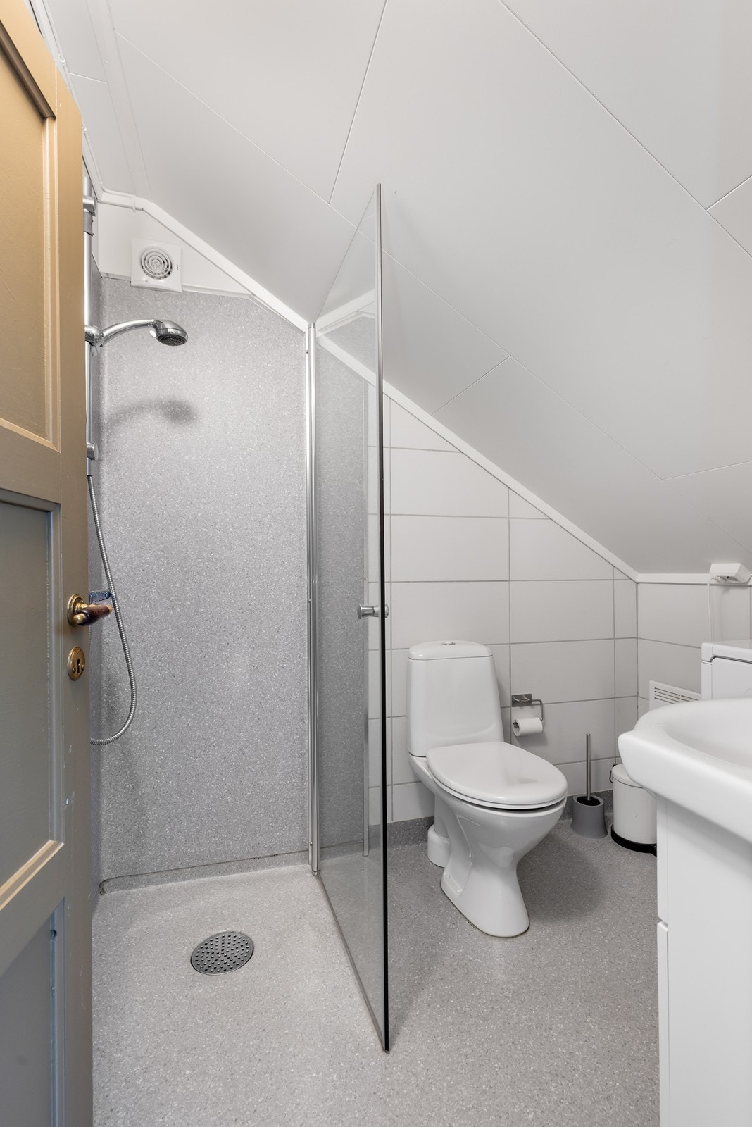 Badet fremstår som lyst og funksjonelt, med servantinnredning, gulvmontert toalett og dusjhjørne. Det er også opplegg for vaskemaskin, noe som gjør rommet praktisk og tilrettelagt for en enkel hverdag. Galleribilde