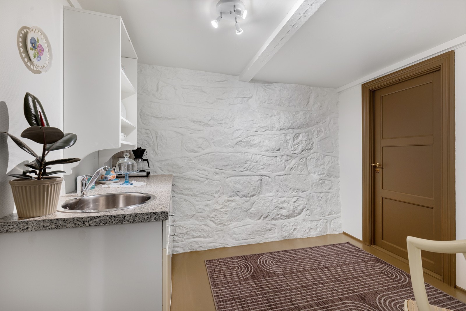Kjøkkenet har en enkel og nyere underskapsinnredning med malte fronter som gir et lyst, rent og ryddig uttrykk. Det er utstyrt med utslagsvask og tilrettelagt plass for oppvaskmaskin. Tilhørende kjøkkenet har du bod til lagring. Galleribilde