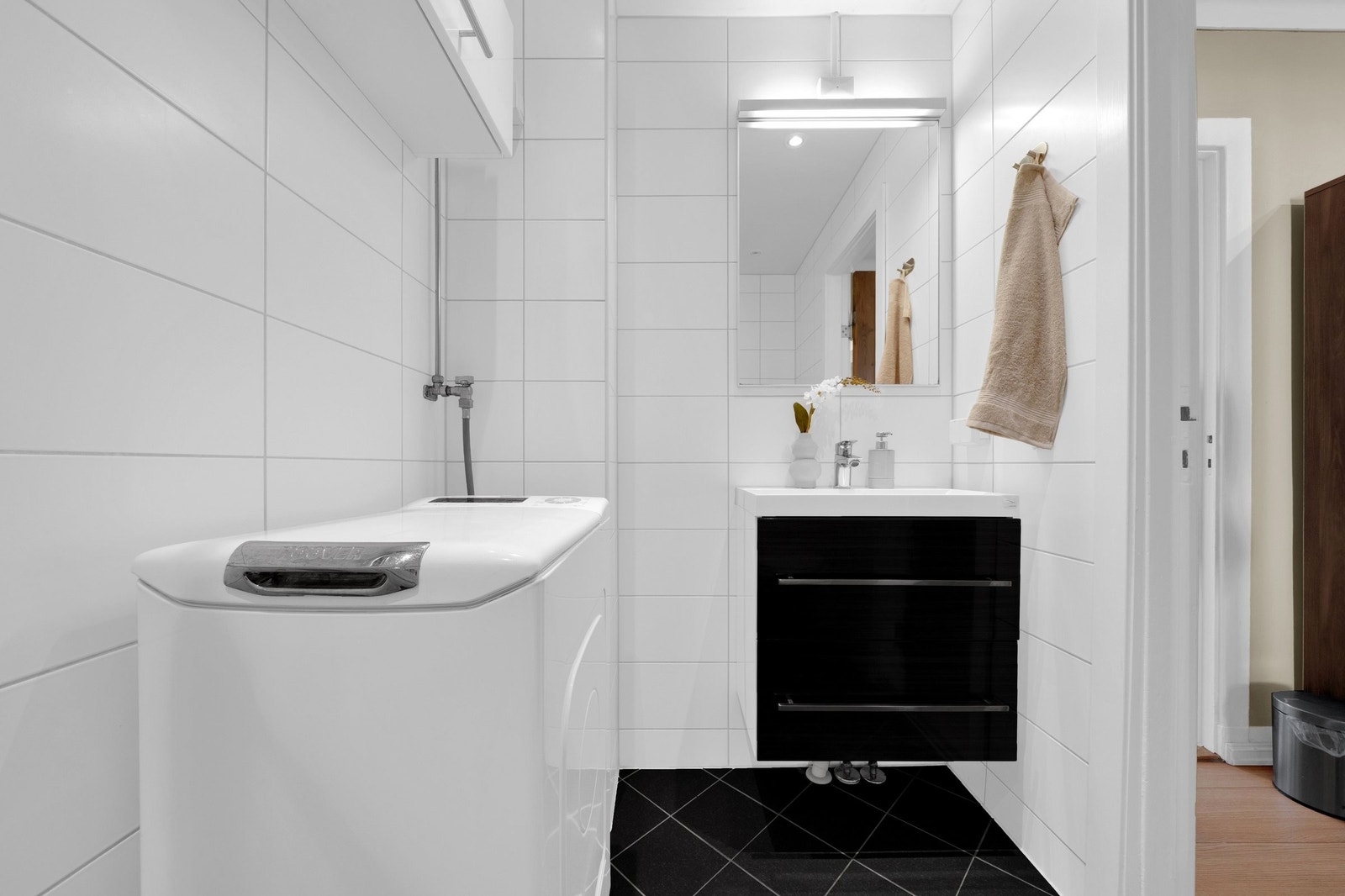 Badet er utstyrt med servantinnredning, dusjhjørne, toalett og opplegg for vaskemaskin. Galleribilde