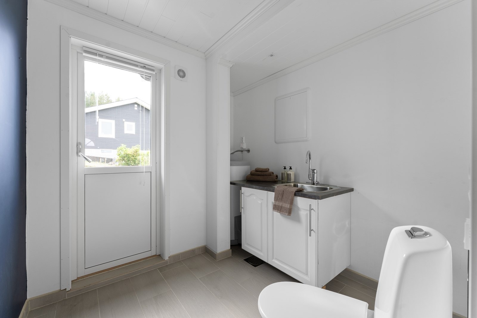 Rommet har innredning med profilerte fronter, laminat benkeplate og nedfelt stålkum, samt opplegg for vaskemaskin og gulvmontert toalett. Galleribilde