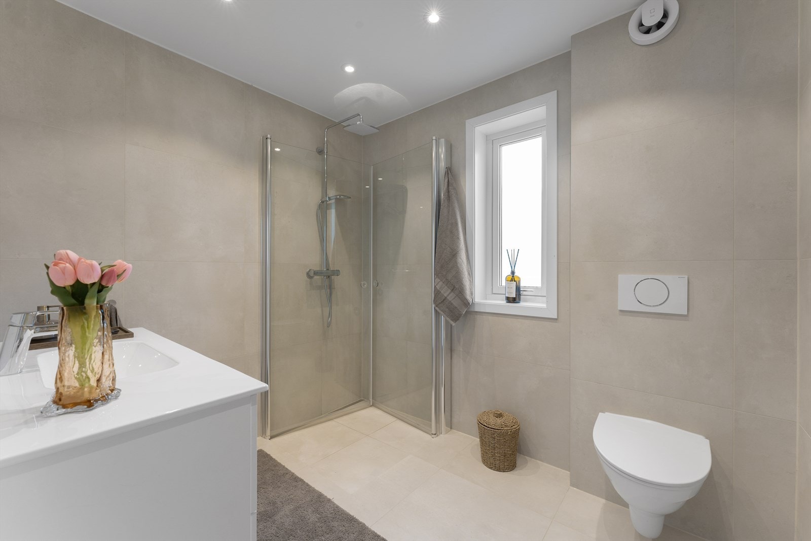 Badet er pusset opp i 2023, med flislagte vegger og gulv, elektriske varmekabler og malt himling med innfelte spotter. Galleribilde