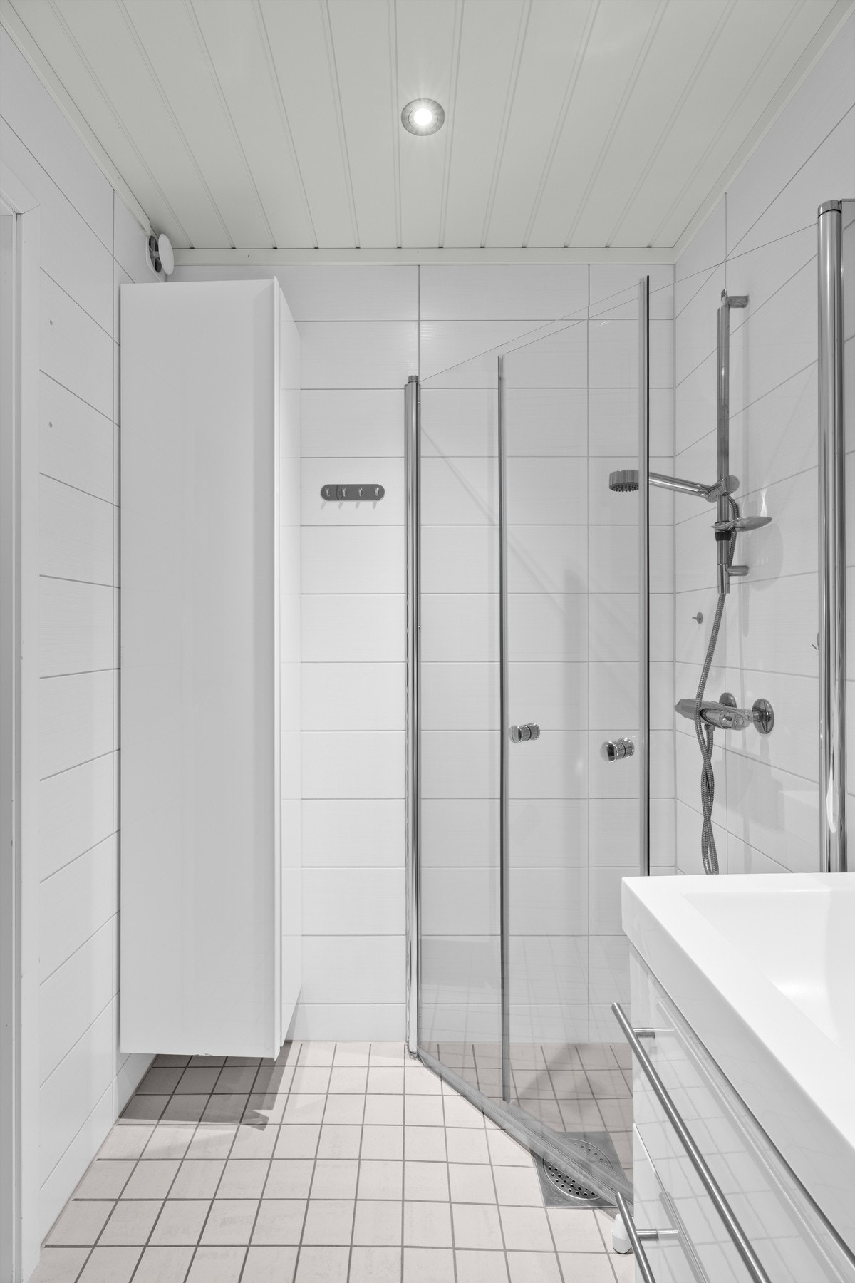 Badet har ellers dusjsone adskilt med to skyvbare glassdører og et høyskap for lagring. Galleribilde
