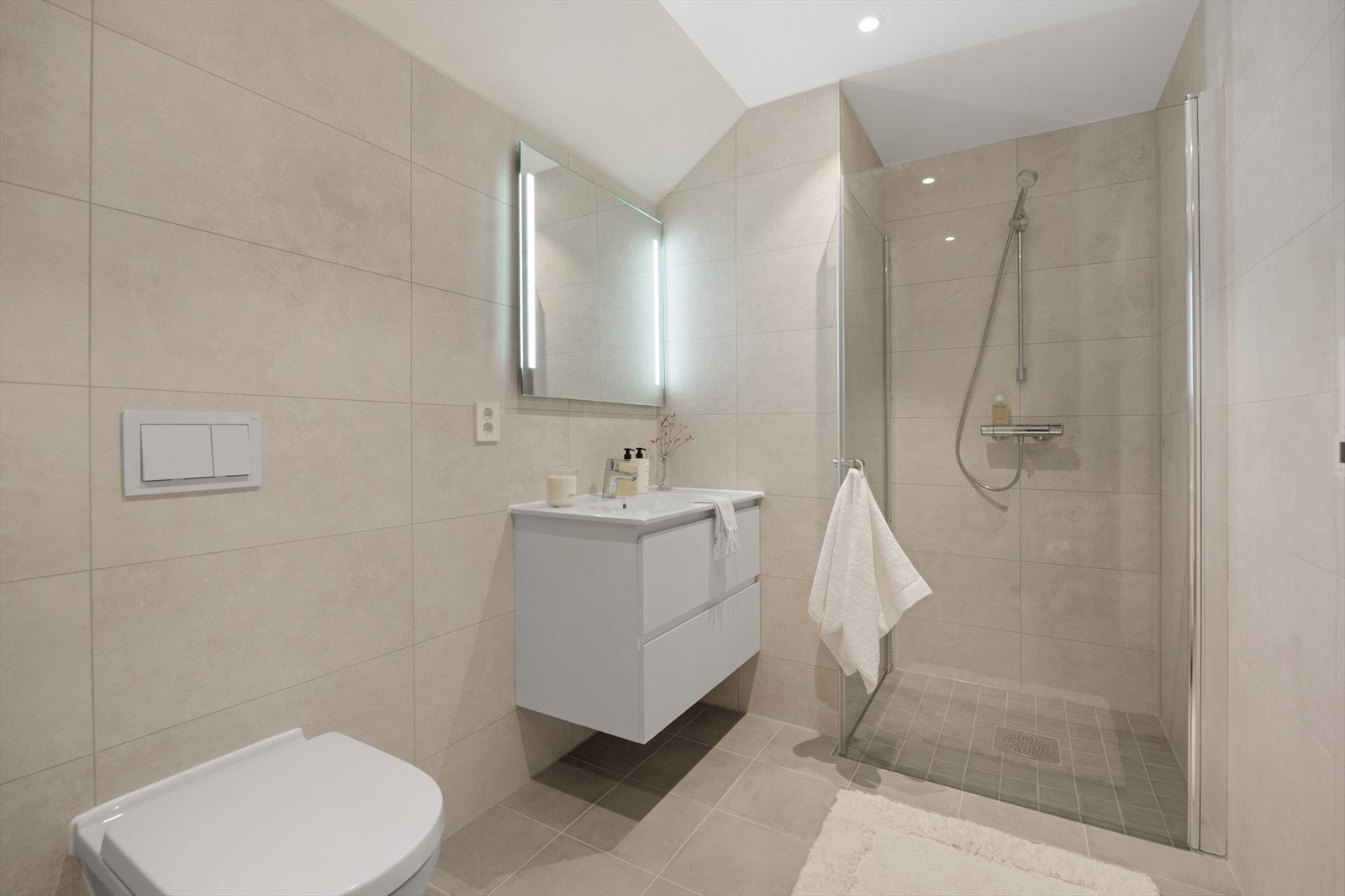 Badet i den øvre etasjen har et moderne og tidløst uttrykk med lysegrå fliser på gulv og større fliser på veggene. Galleribilde