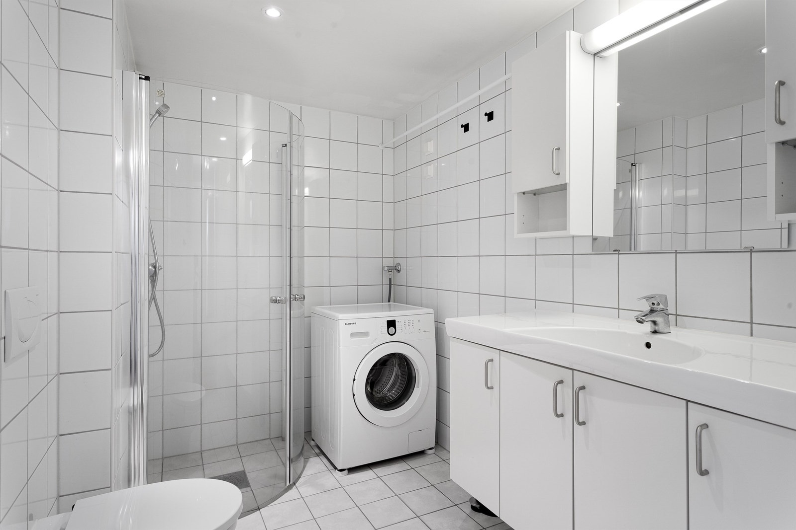 Badet har vegghengt toalett, dusjhjørne og vaskemaskin. Galleribilde