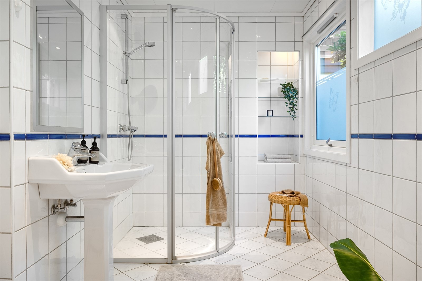Badet har flislagte gulv og vegger. Rommet er innredet med dusj, servant, toalett og opplegg for vaskemaskin. Galleribilde
