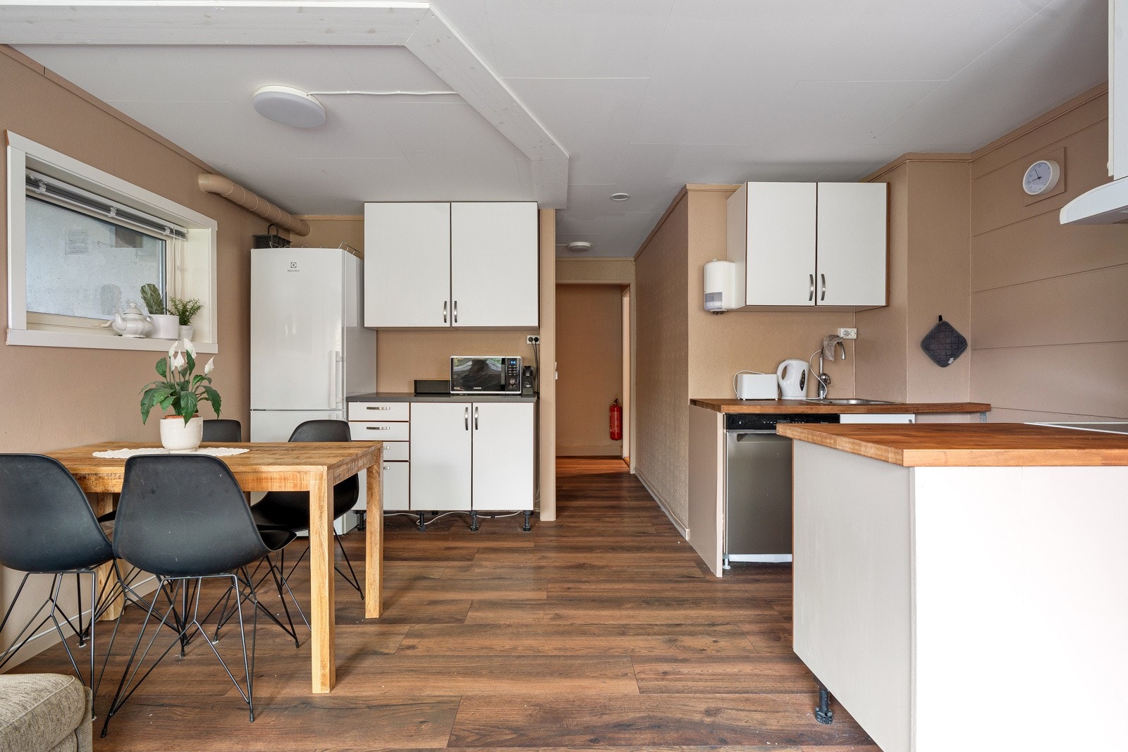 Kjøkken med glatte fronter og benkeplate i laminat og heltre. I tilnytning kjøkkenet er det også plass til et spisebord.