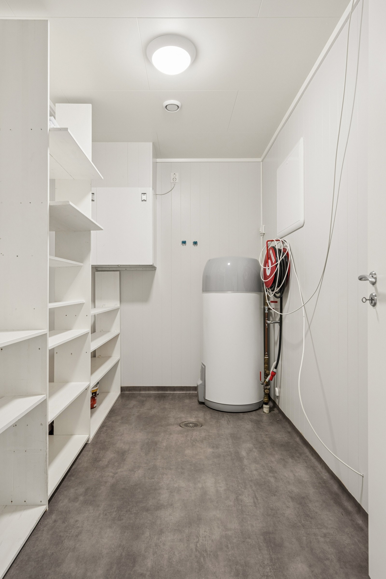 Innvendig bod på ca. 6 m², med gulvbelegg og praktiske hyller som gir gode oppbevaringsmuligheter.