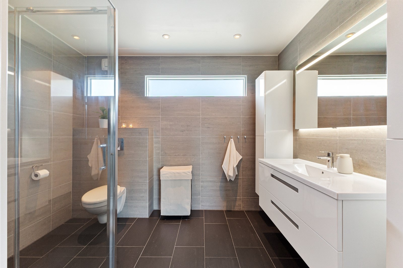 Badet har flislagte overflater og gir et lyst inntrykk med vindu som slipper inn naturlig lys. Galleribilde