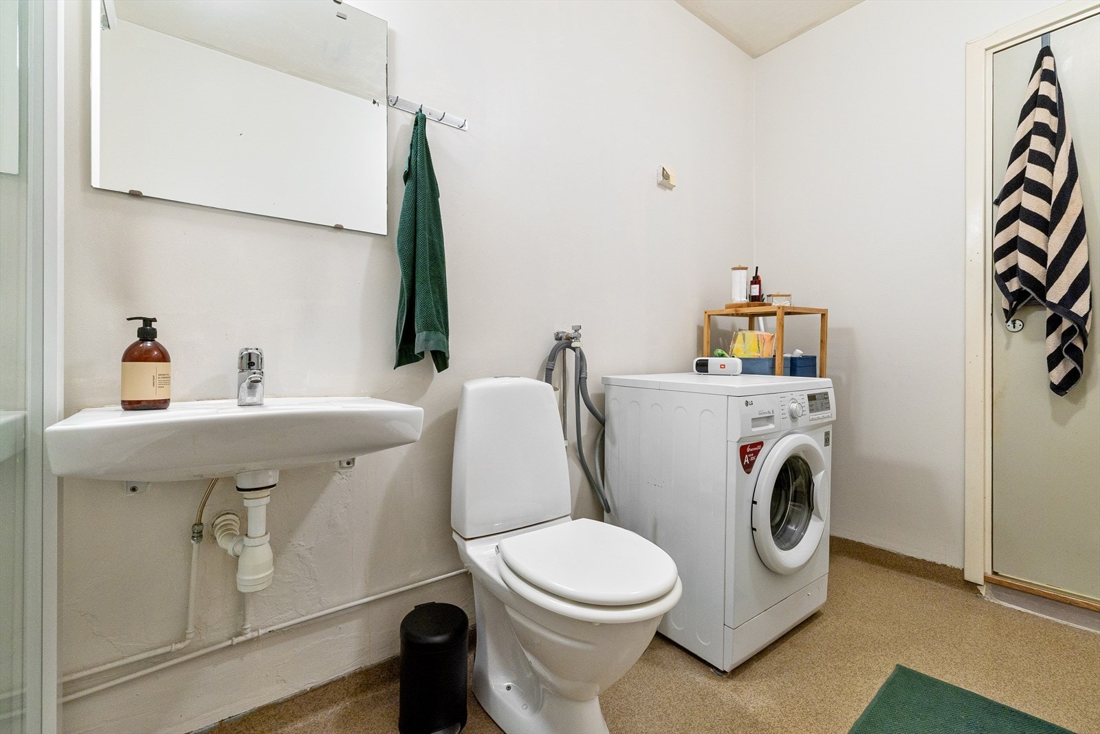 Badet er utstyrt med dusjkabinett, gulvmontert toalett, hvit servant med Oras-blandebatteri. Galleribilde