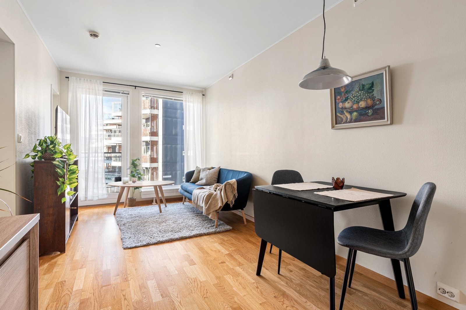 Den åpne stue- og kjøkkenløsningen skaper et lyst og luftig oppholdsrom med god plass til både sofagruppe og spisebord. Store vindusflater slipper inn rikelig med dagslys og gir rommet en innbydende atmosfære.