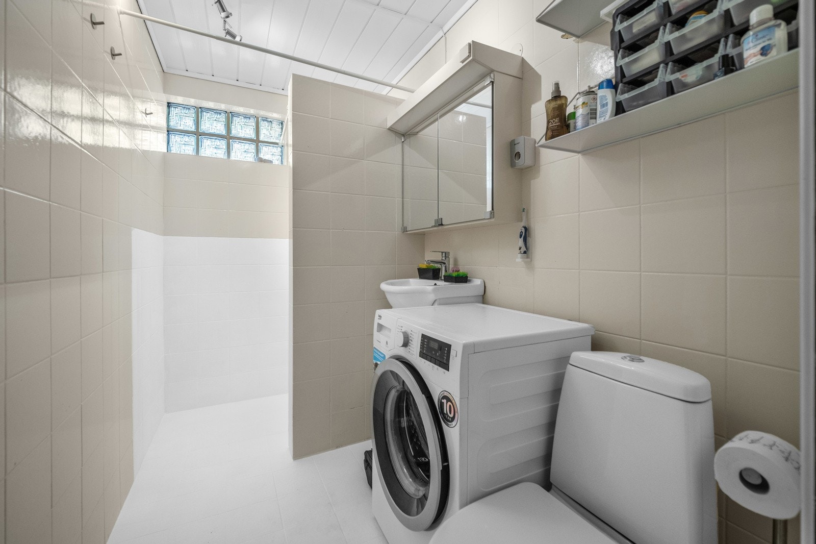 Lyst bad med nedfelt servant, toalett, dusjhjørne og opplegg for vaskemaskin Galleribilde