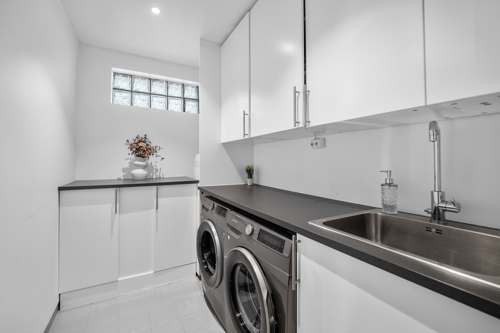 Praktisk vaskerom i underetasjen med vask, rikelig med oppbevaringsplass og plass til vaskemaskin og tørketrommel Galleribilde