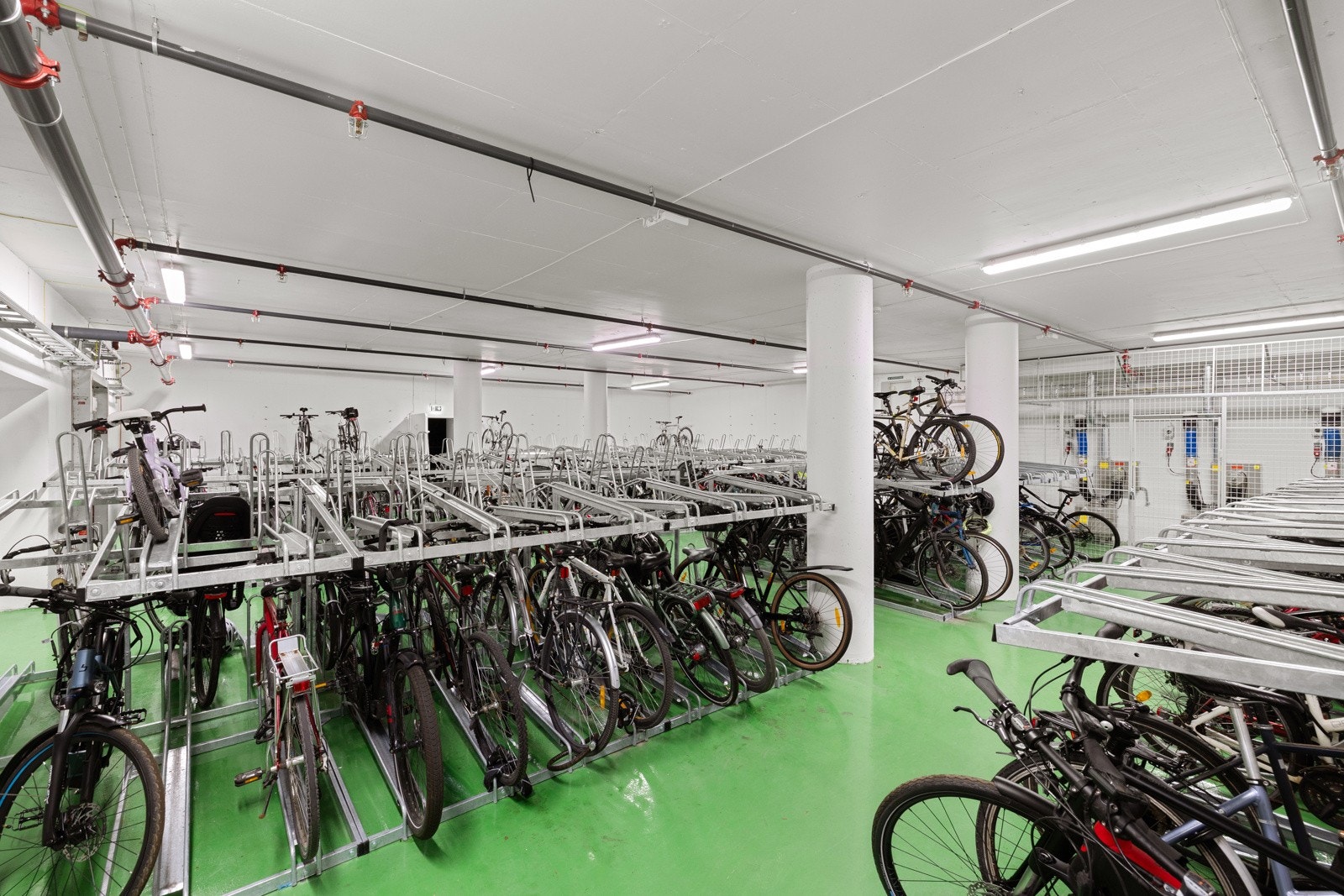 Romslig og oversiktlig felles sykkelparkering i underetasje, med god kapasitet og praktiske stativer som gjør det enkelt å sette fra seg sykkelen trygt. Galleribilde