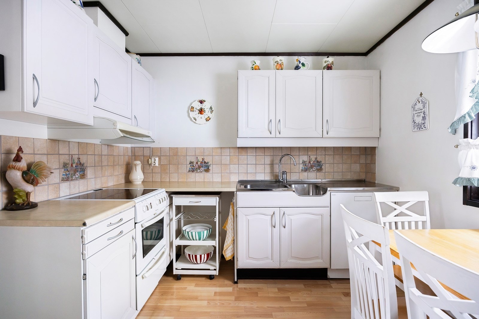 Kjøkkenet er fra byggeår og bærer preg av normal bruksslitasje. Kjøkkeninnredning med profilerte fronter, laminat benkeplate og fliser på vegg over benk. Galleribilde