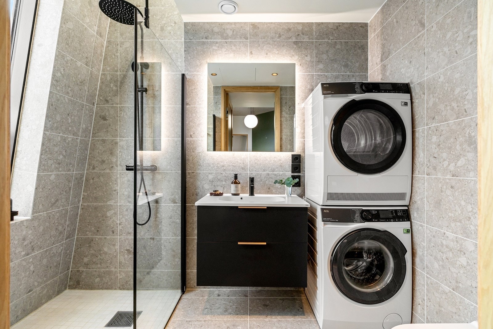 Badet fremstår som moderne og gjennomført, med store, tidløse fliser i rolige naturtoner som gir et helhetlig og rolig uttrykk. Galleribilde