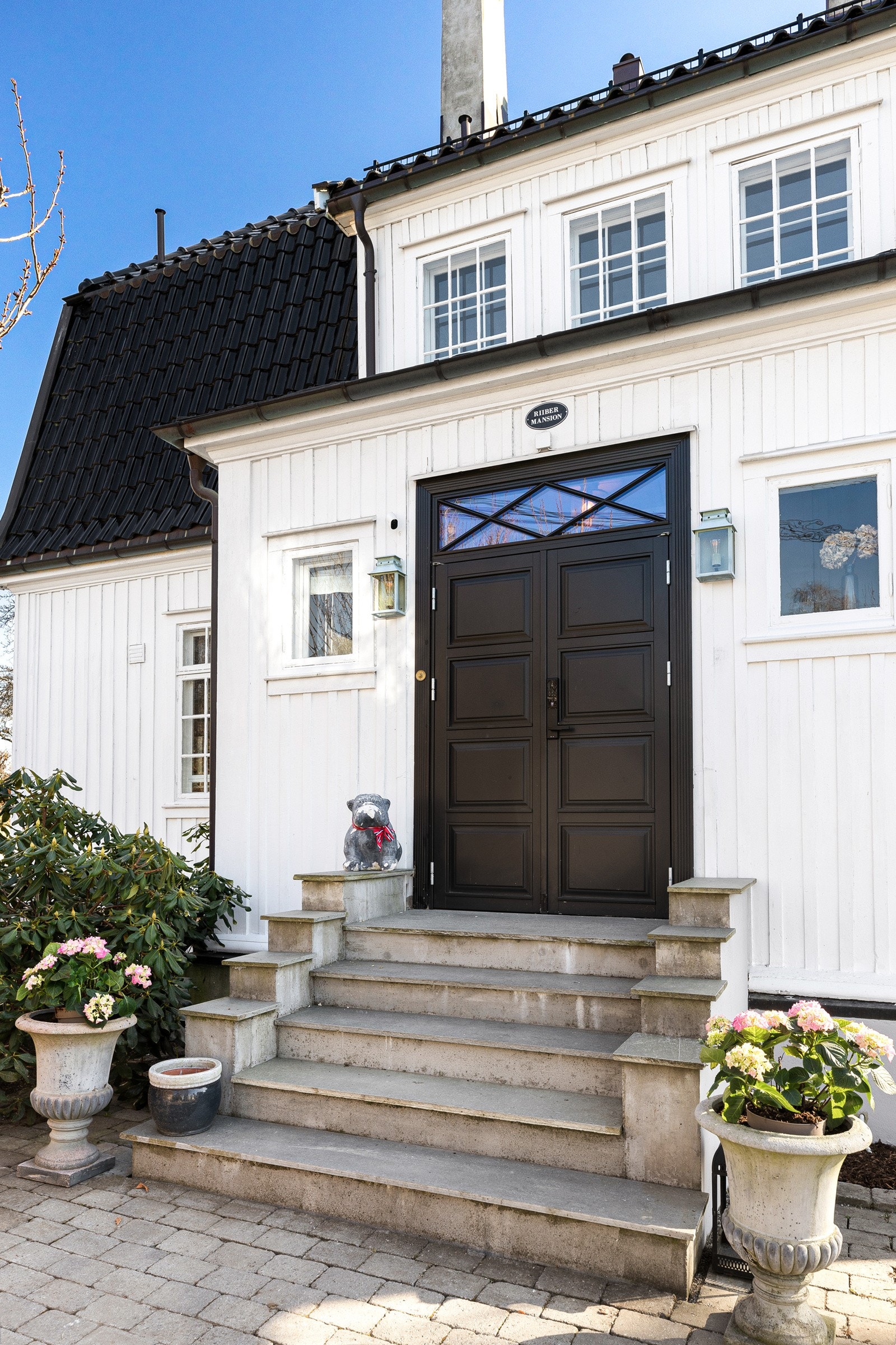 Villaen har adkomst via skiferbelagt trapp til en tofløyet inngangsdør med kodelås. Galleribilde