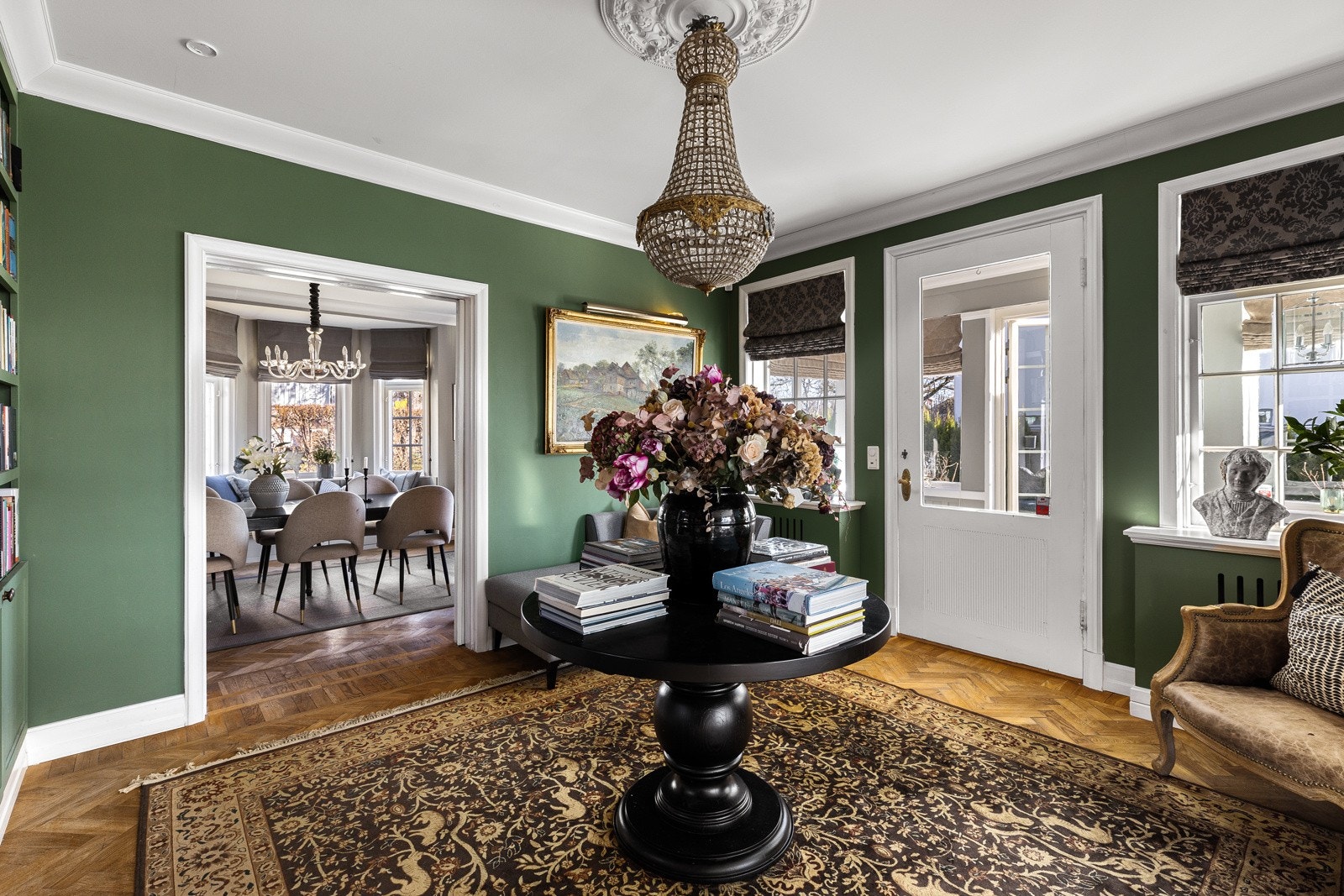 Den grønnmalte stuen har utgang til vinterhagen, tofløyet skyvedør til spisestuen og åpen løsning mot hovedstuen. Galleribilde