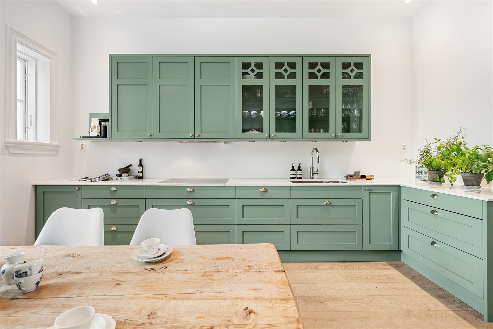 Smakfull innredning fra Smedstorp med grønne, profilerte fronter, enkelte fronter med glass og Silestone 20 mm arier benkeplate. Galleribilde